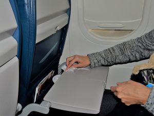 Passenger wiping down tray table on airplane