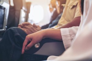 Passenger sitting in seat on airplane with their arm on armrest