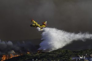 Firefighting airplane dropping water on wildfire while in flight
