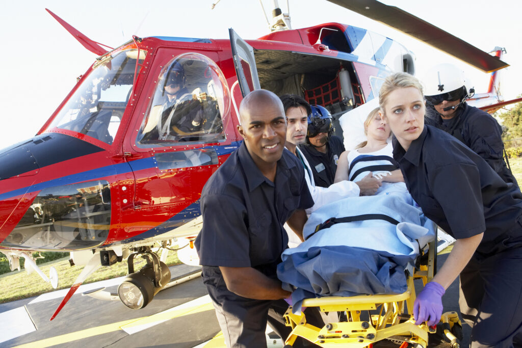 Medical team transporting patient on a stretcher from helicopter. 