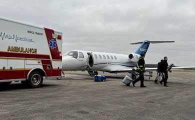 Ambulance and airplane parked on airstrip at airport.
