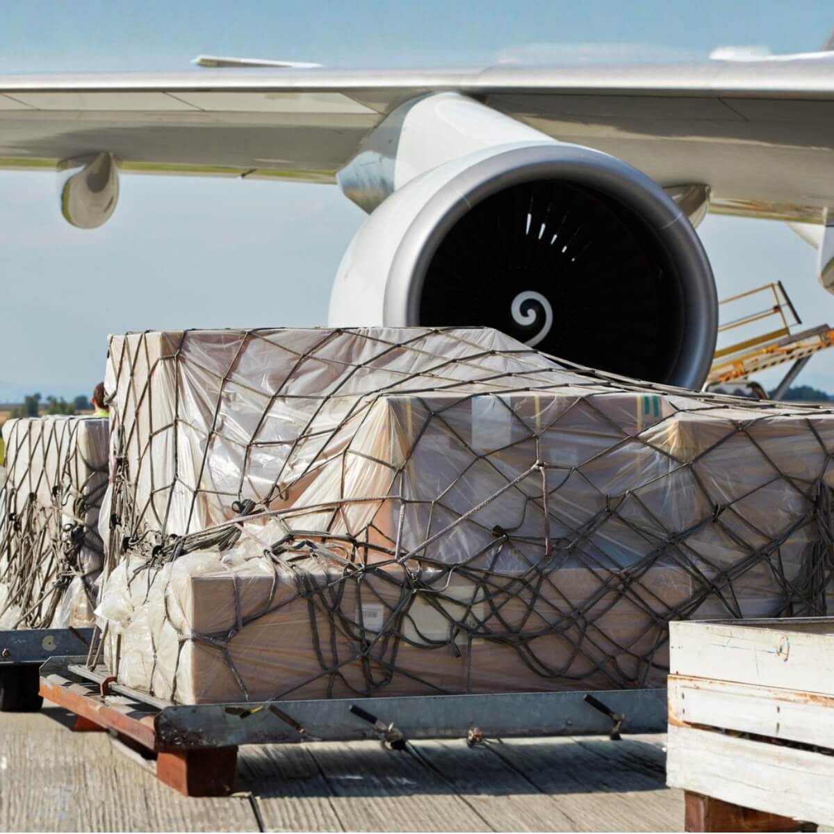 cargo on pallets in front of plane engine