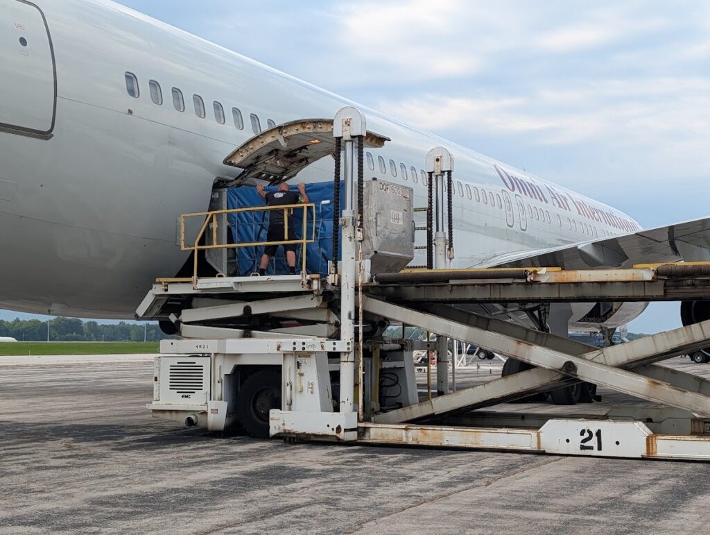 Grand Aire employee guiding freight into a commercial airplane